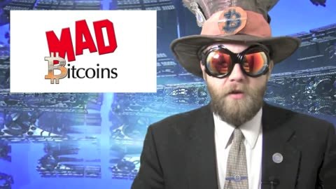 Thumbnail of the 27 January 2014 Mad Bitcoins episode: a bearded presenter in a dark suit, goggles and a top hat, against a blue graphic background, beside the Mad Bitcoins logo.