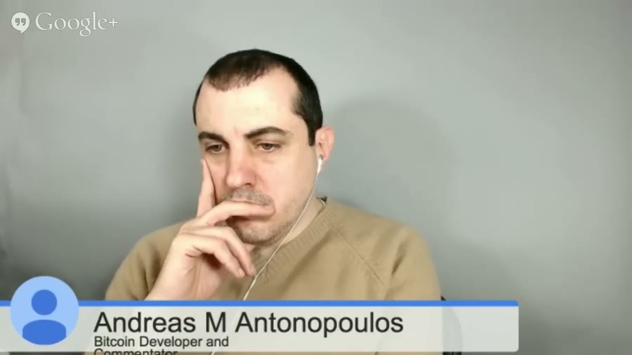A Google+ Hangout video tile showing a man in a tan jumper with earphones, resting his chin on his hand, with a lower-third caption reading Andreas M Antonopoulos, Bitcoin Developer and Commentator.