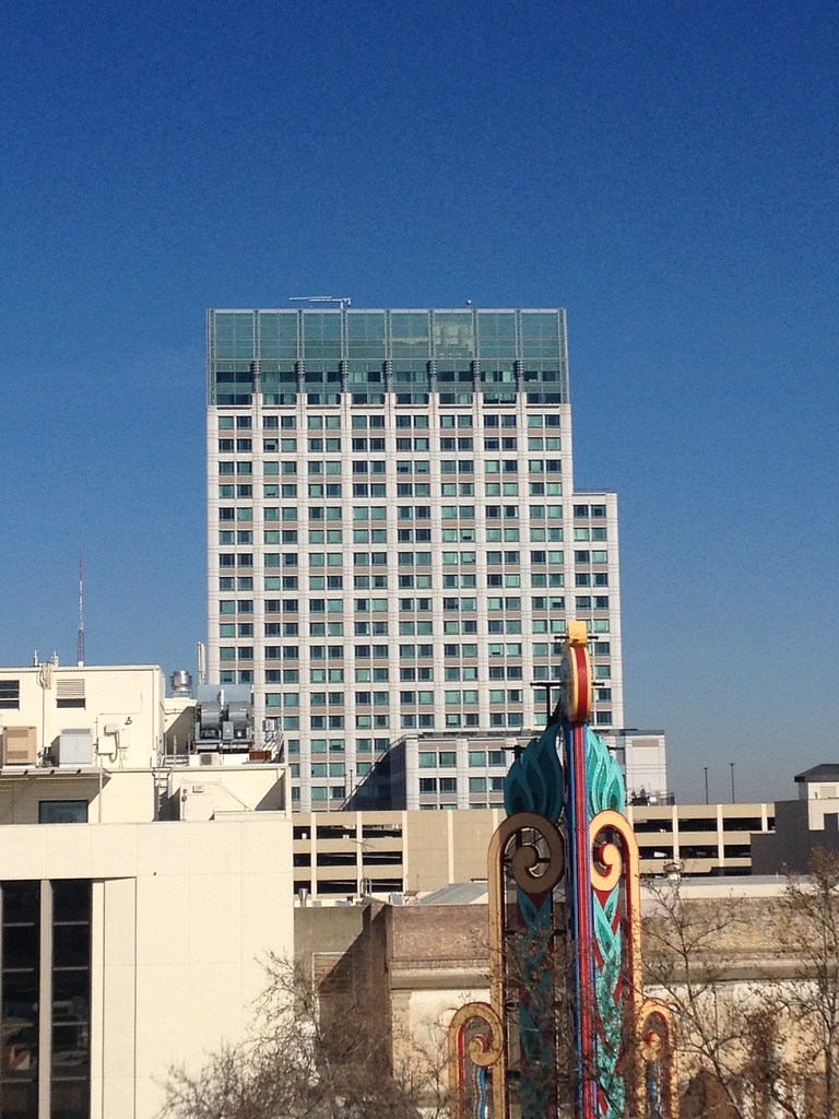The vertical Crest sign appears in front of a rectangular city building.