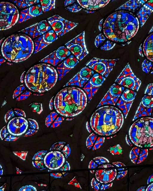 Intricate circles of blue, red and gold stained glass viewed at an angle.